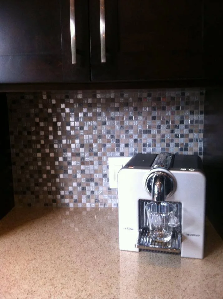 A coffee machine on a kitchen countertop with a glass cup positioned under the dispenser.