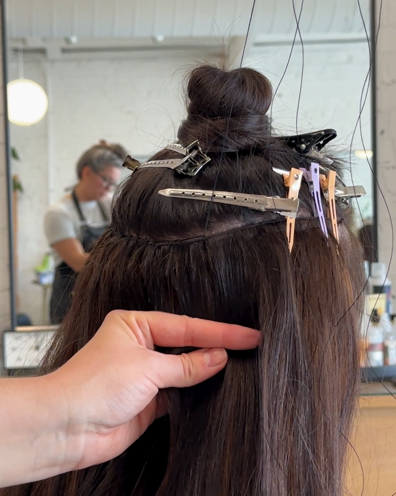 Hair extensions being sewn into hair at a salon