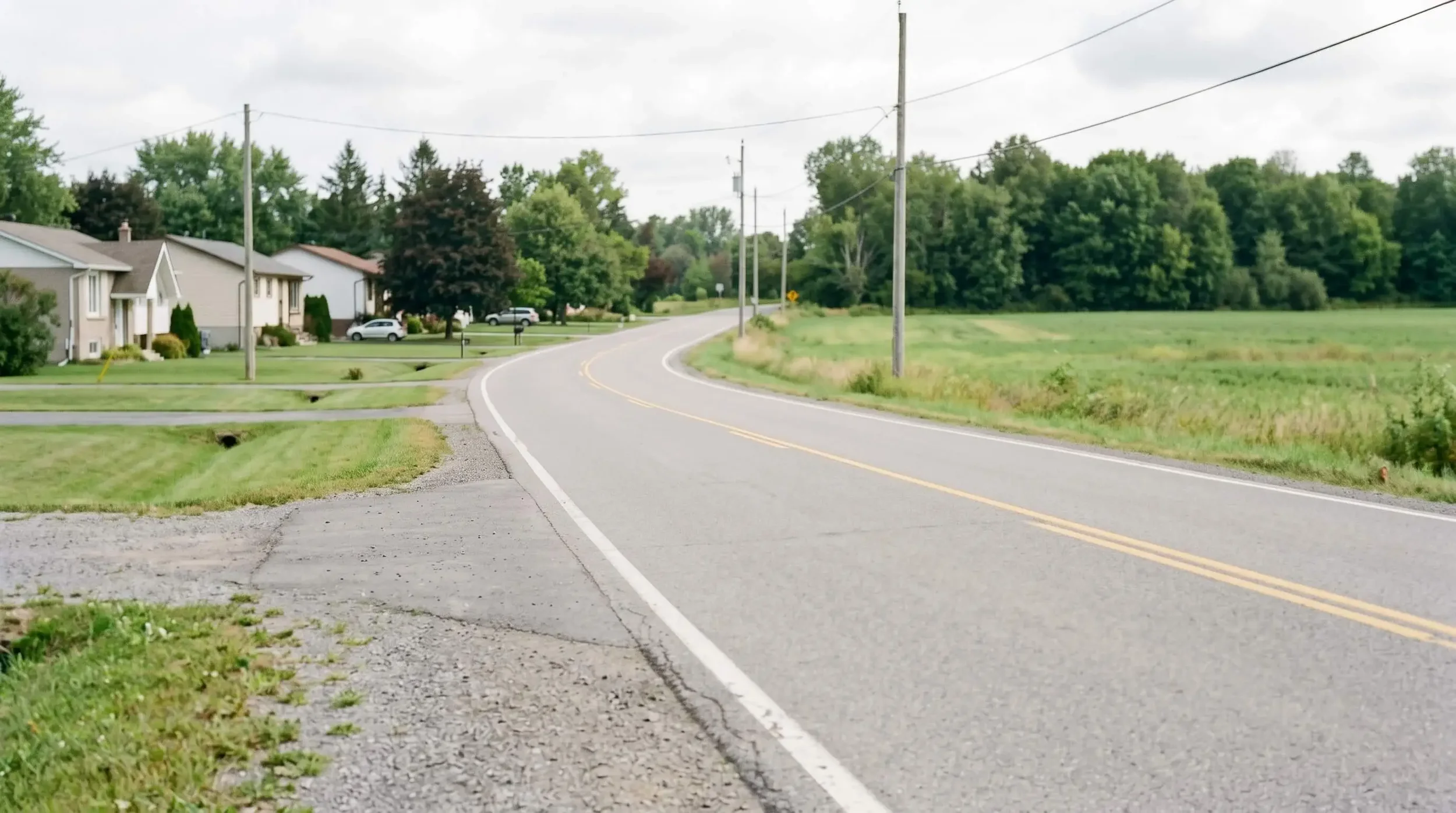 Rural road in west Ottawa near Carp and Dunrobin transitioning from suburban Kanata neighbourhoods to open countryside with mature trees