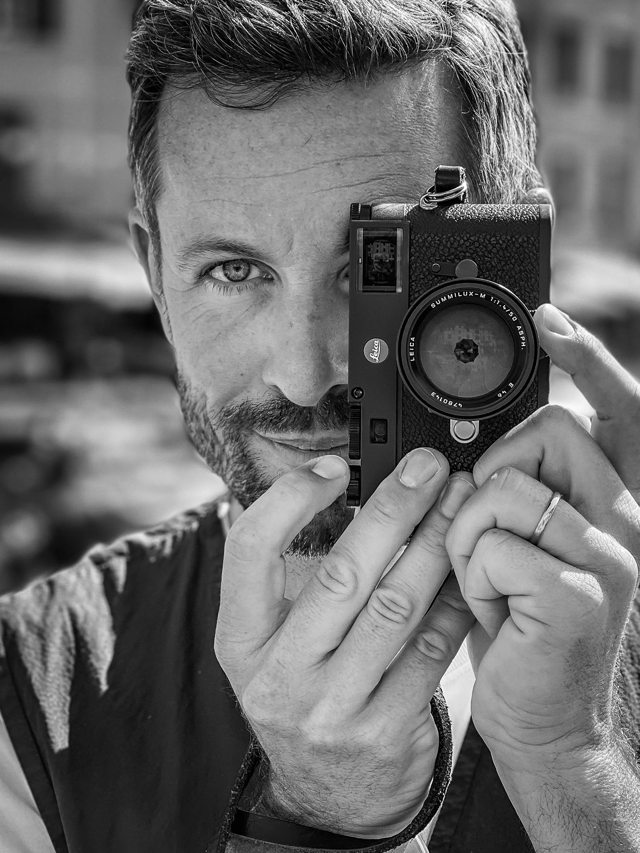 Schwarz-weiß-Foto von Schauspieler Jan Hartmann, der eine Kamera vor sein Gesicht hält und durch den Sucher schaut.