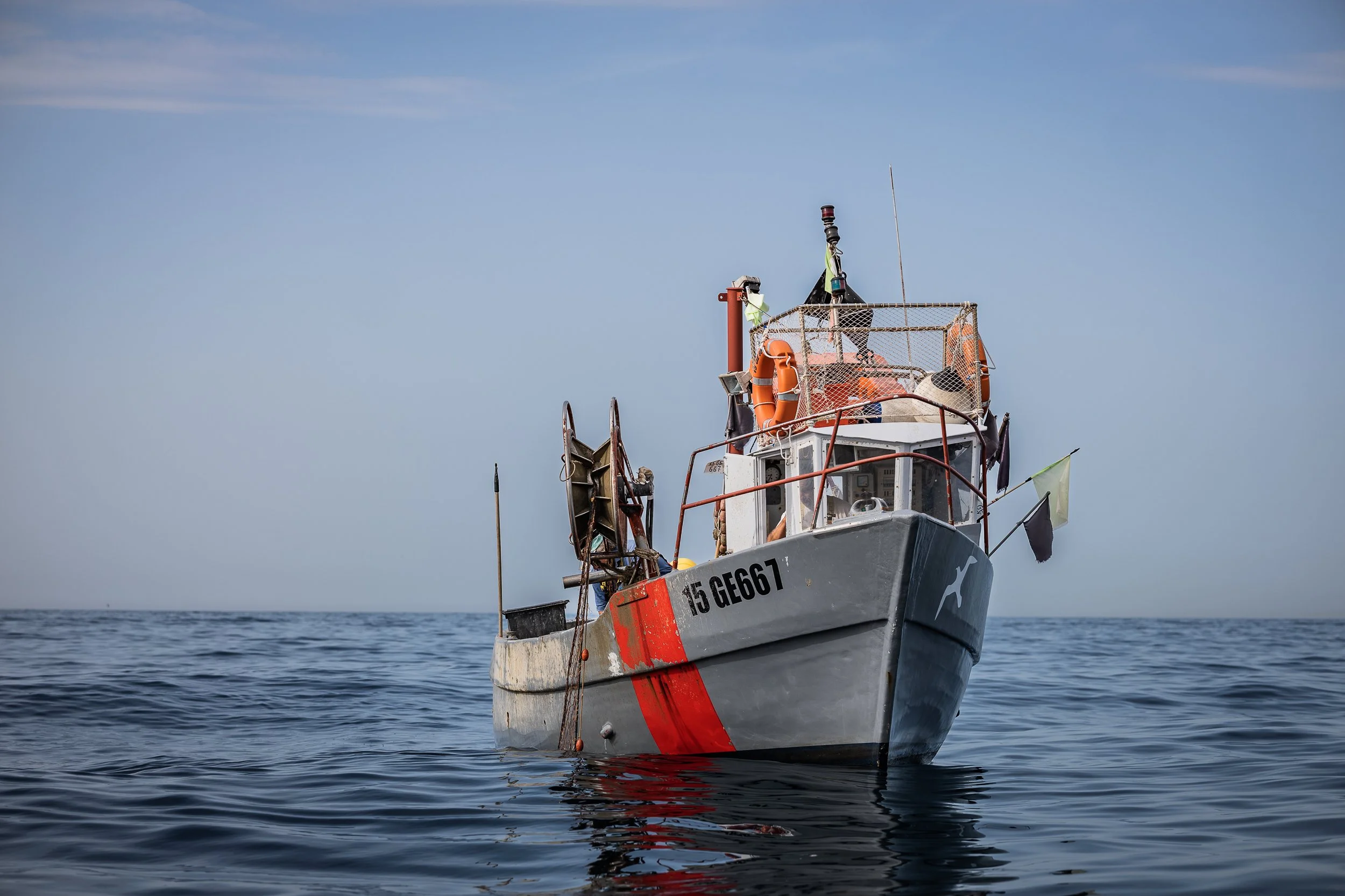 Ligurien, Italien. Ein Fischereiboot auf dem Meer, mit Rettungsringen und Flaggen an Bord.