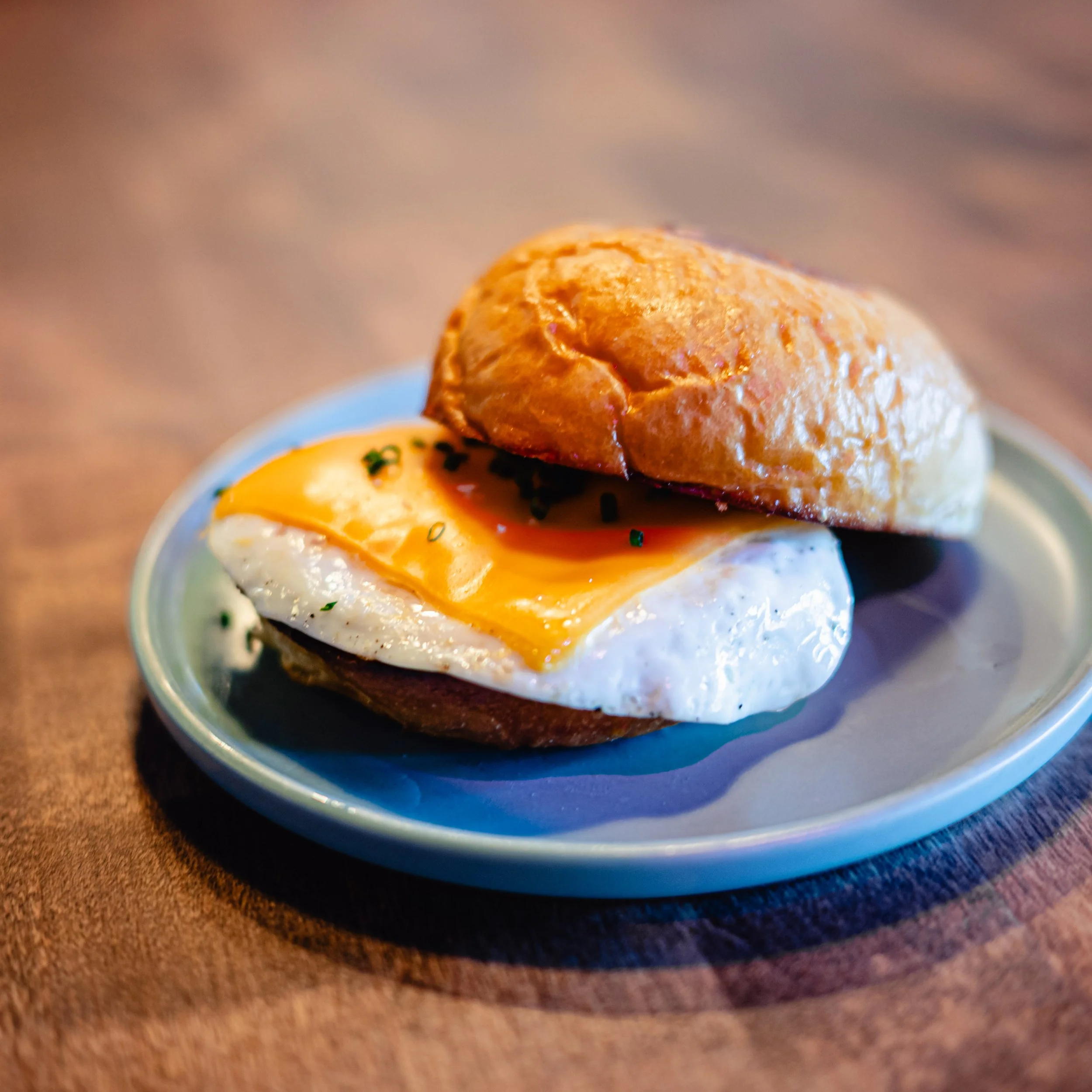 Eggs Benedict on a small plate, with a toasted bun, fried egg, and hollandaise sauce.