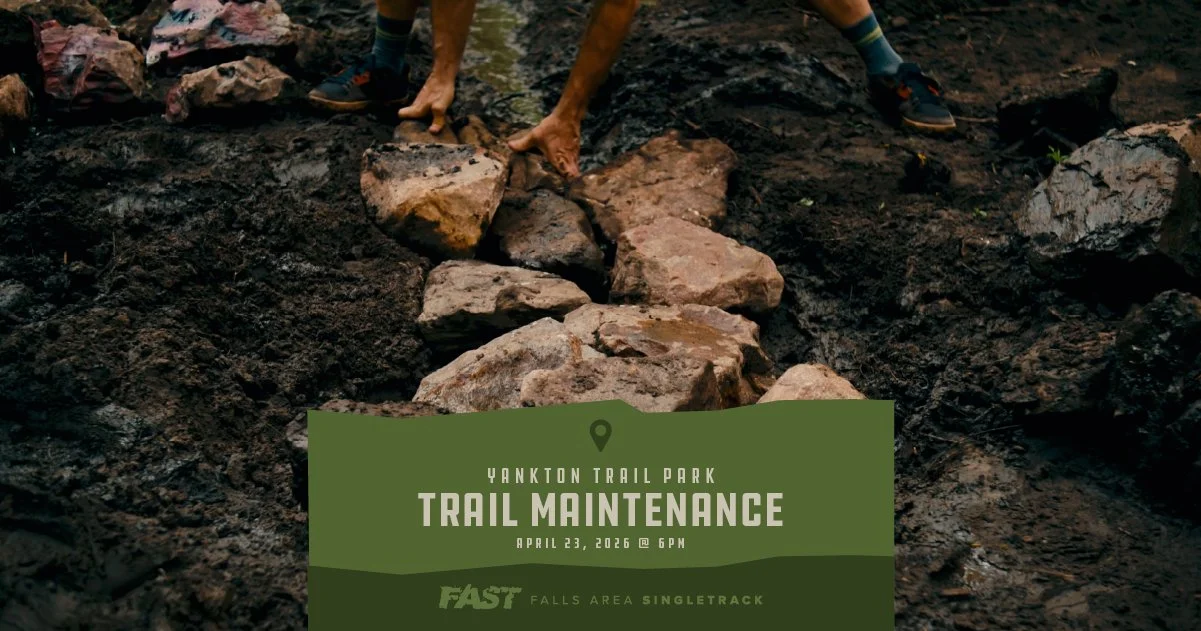 Trail maintenance, man moving rocks in wet soil.