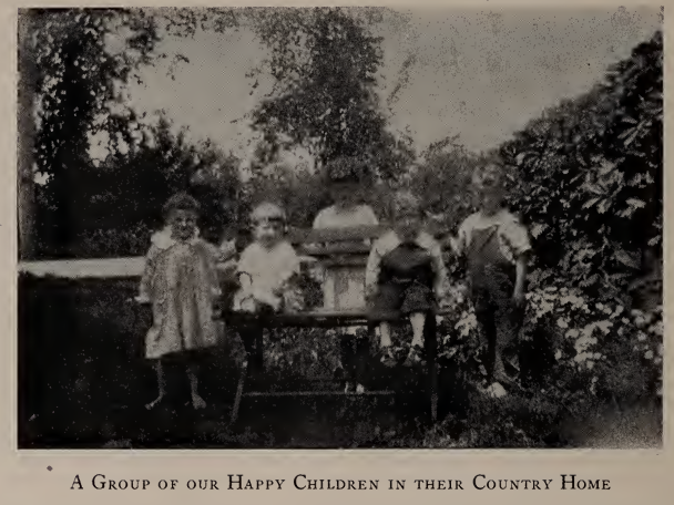Photo of five children gathered outdoors in a garden area, captioned "A Group of our Happy Children in their Country Home," from the 1923 Annual Report of the Avon Home.