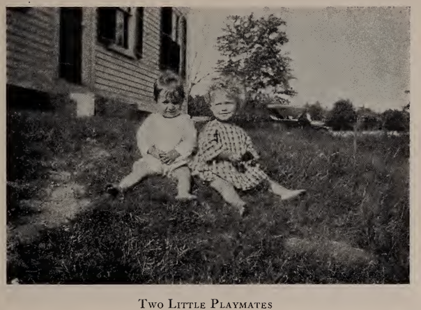 Photo of two young children seated together on the grass outside a home, captioned "Two Little Playmates," from the 1923 Annual Report of the Avon Home.