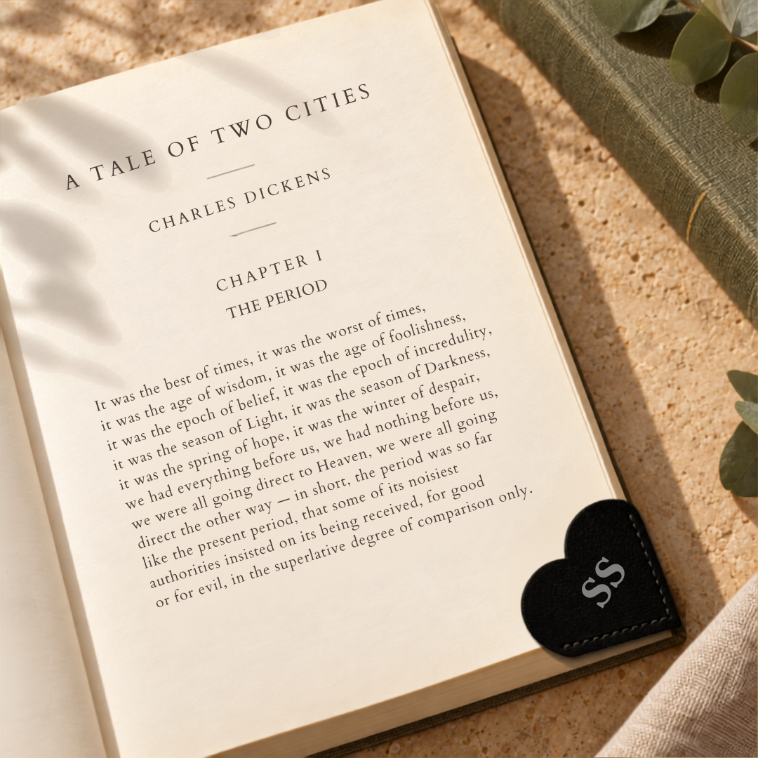 Personalised black vegan leather heart-shaped corner bookmark on the page of an open book.