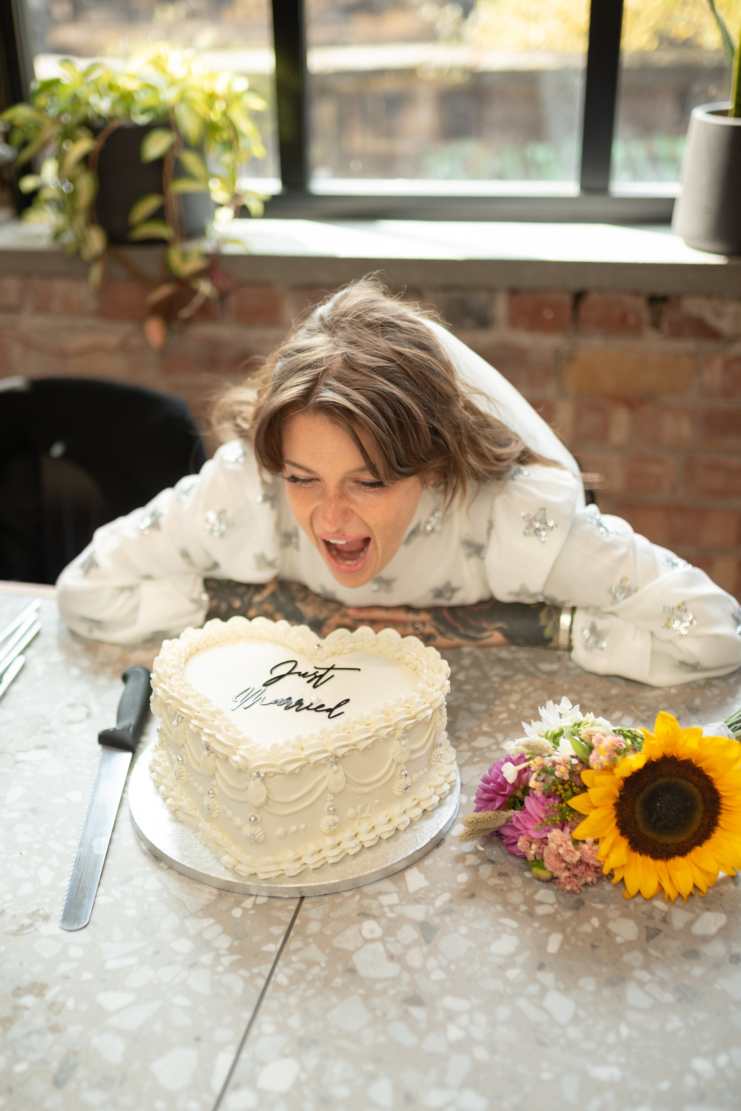 Woman leaning over a heart-shaped wedding cake with 'Just Married' written on it