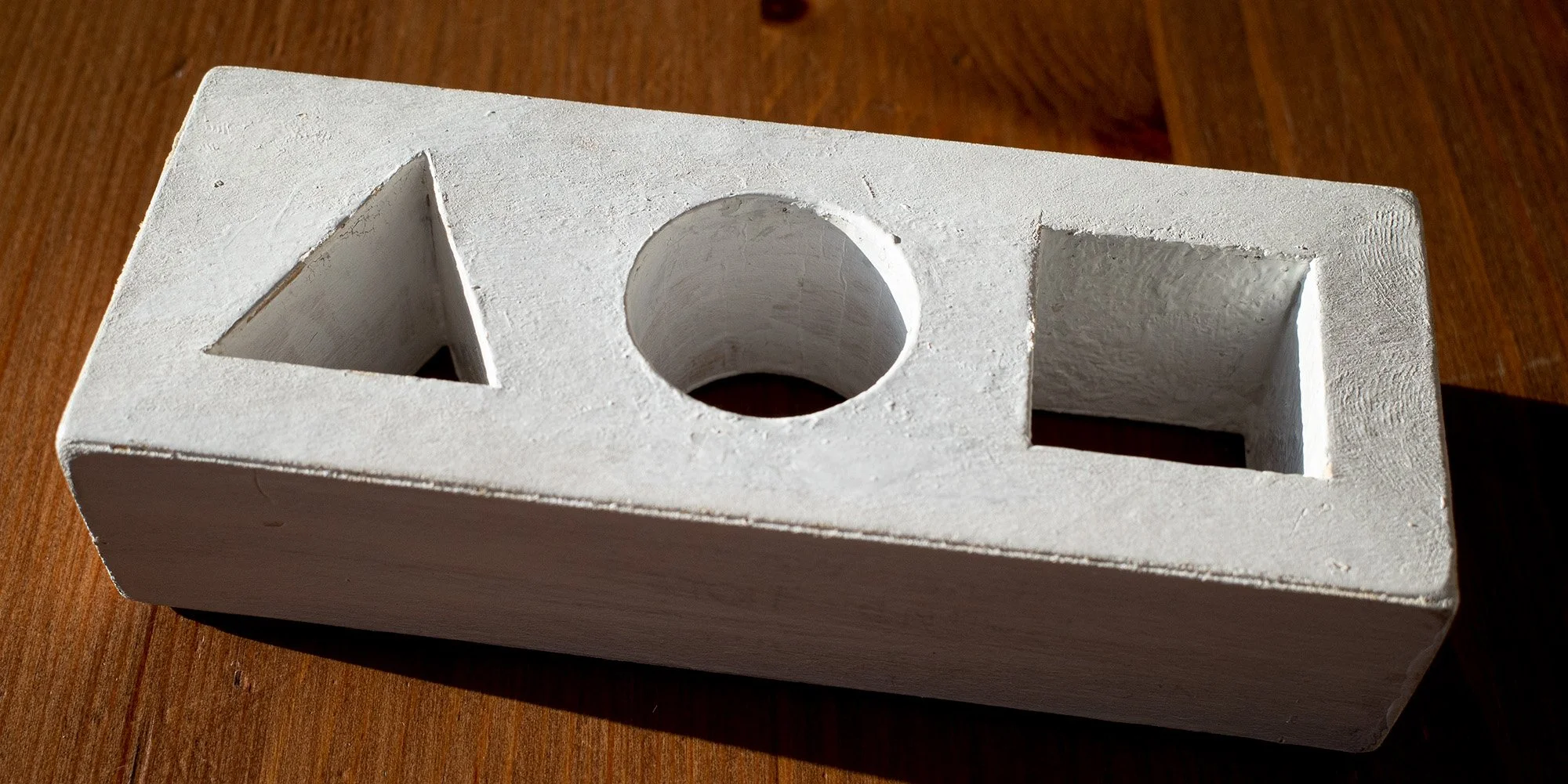 Styrofoam block with triangle, circle, and square carved out