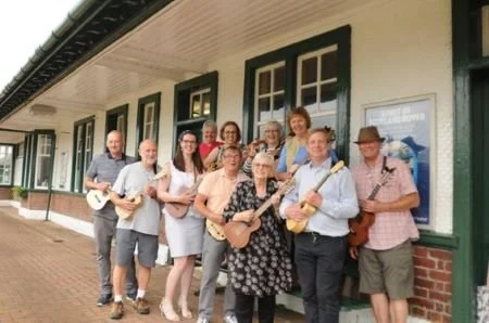Ukulele group pose with ukuleles.