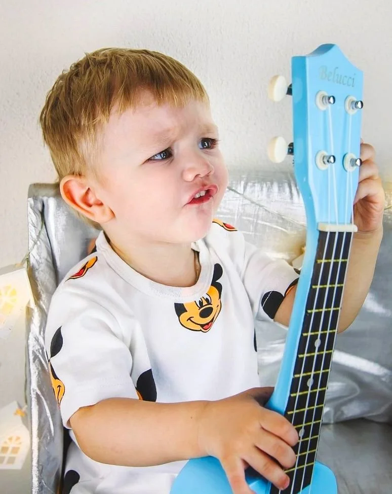 Boy tuning a blue ukulele.