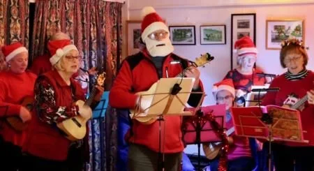 Christmas group singing and playing ukuleles.