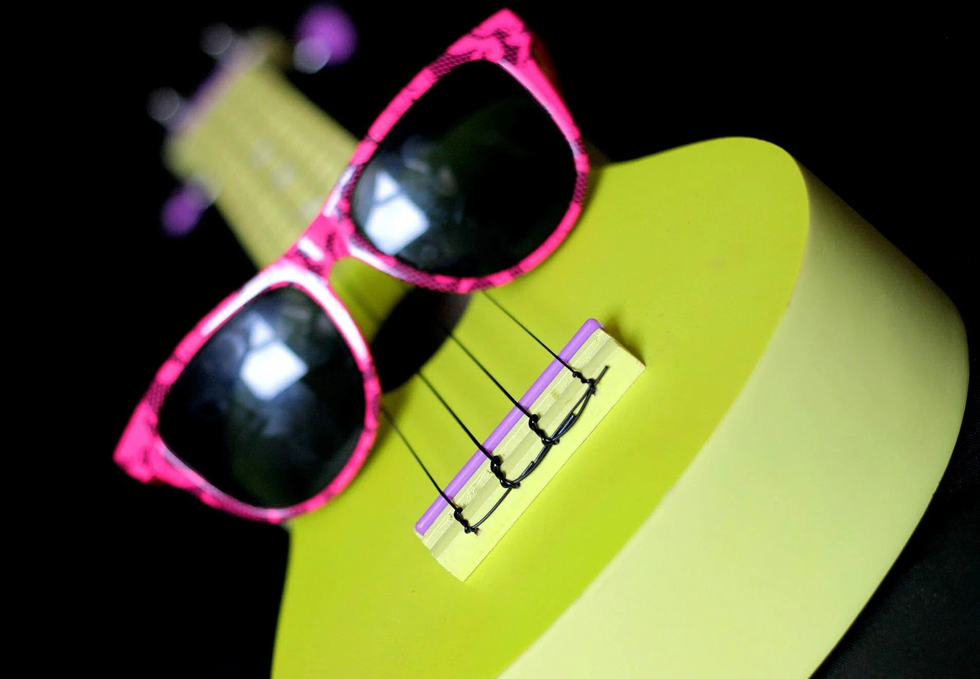 Close up of the green Ukuleles Unanimous ukulele with pink sunglasses.