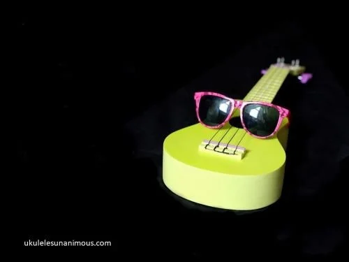 Green ukulele with pink sunglasses.