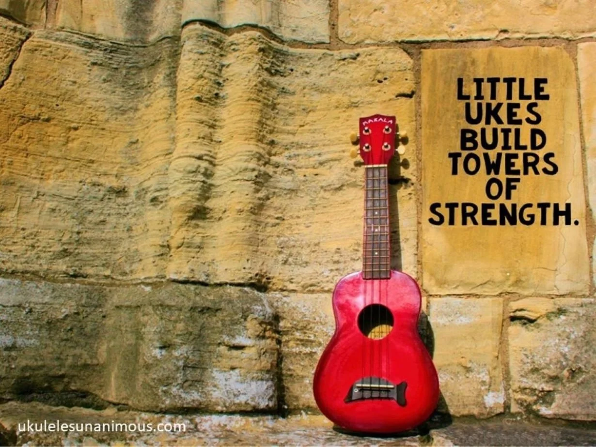Small red ukulele leaning against a strong stone wall.
