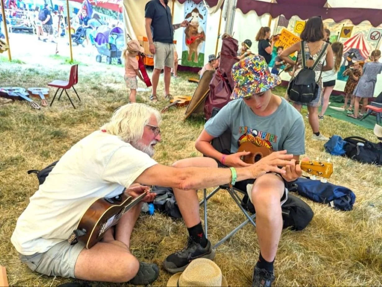 Ukulele teacher with student at festival.