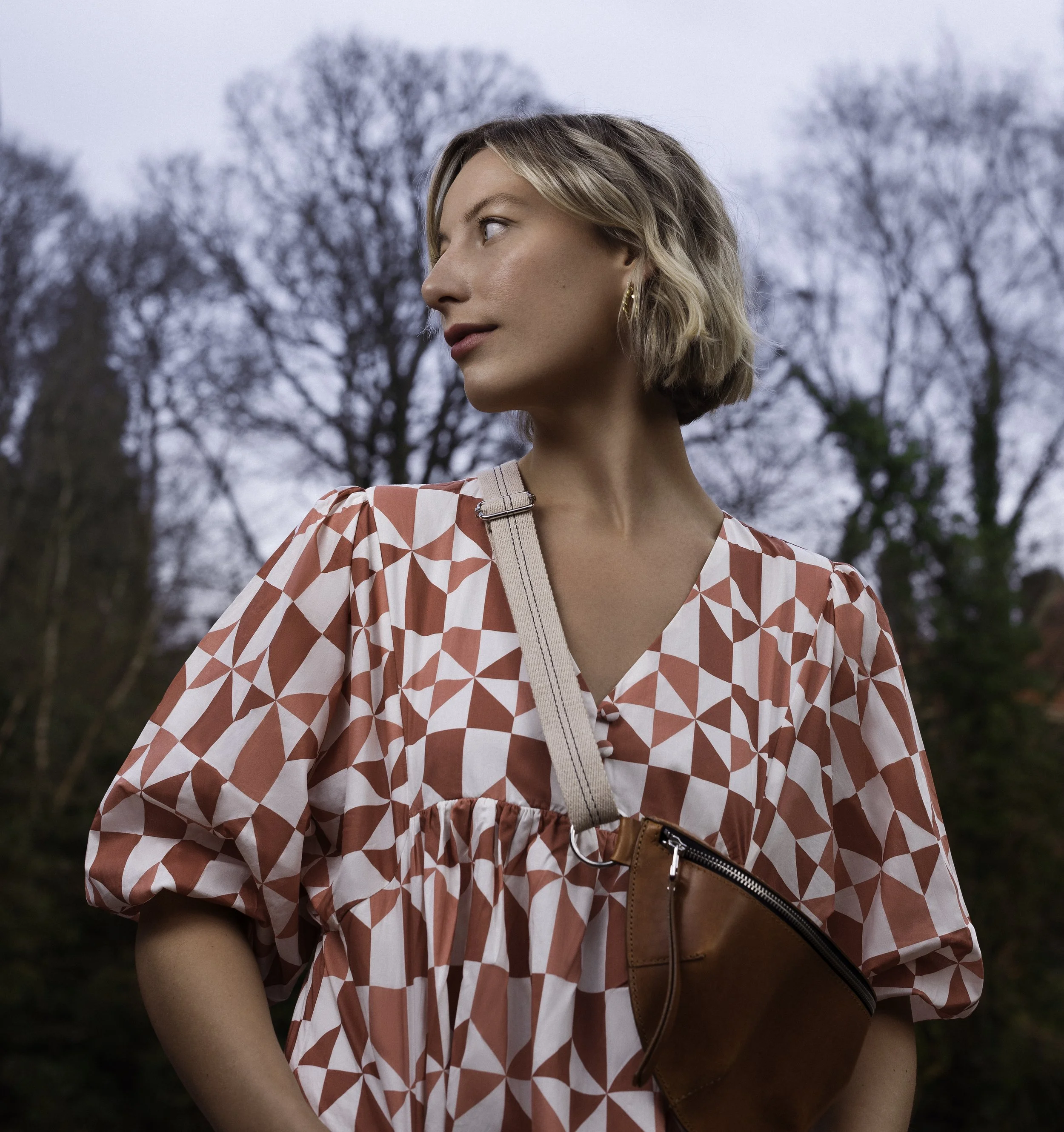 location portrait photograph of woman standing in front of trees