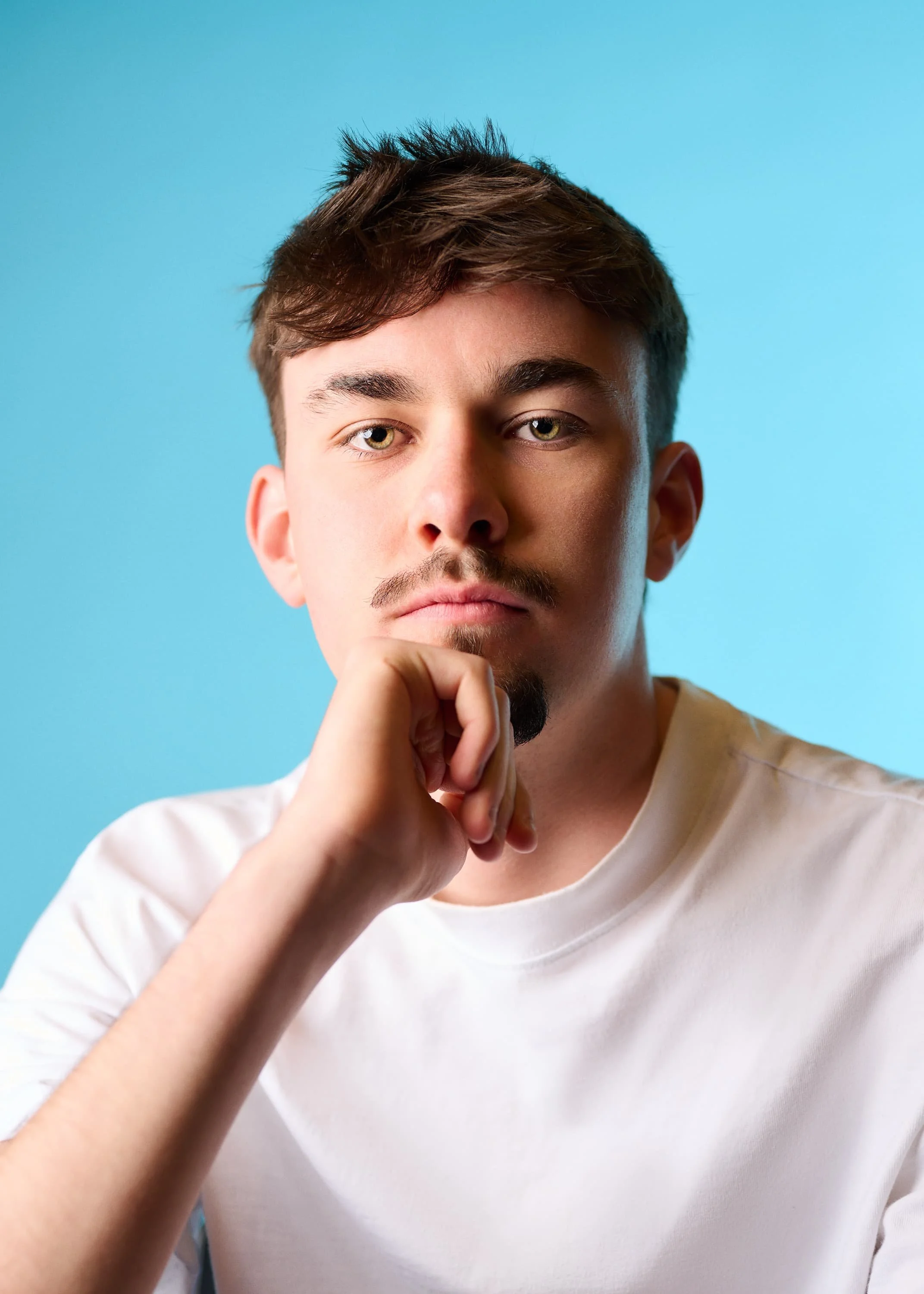 Colour portrait of an actor resting his chin on my hand looking into the camera