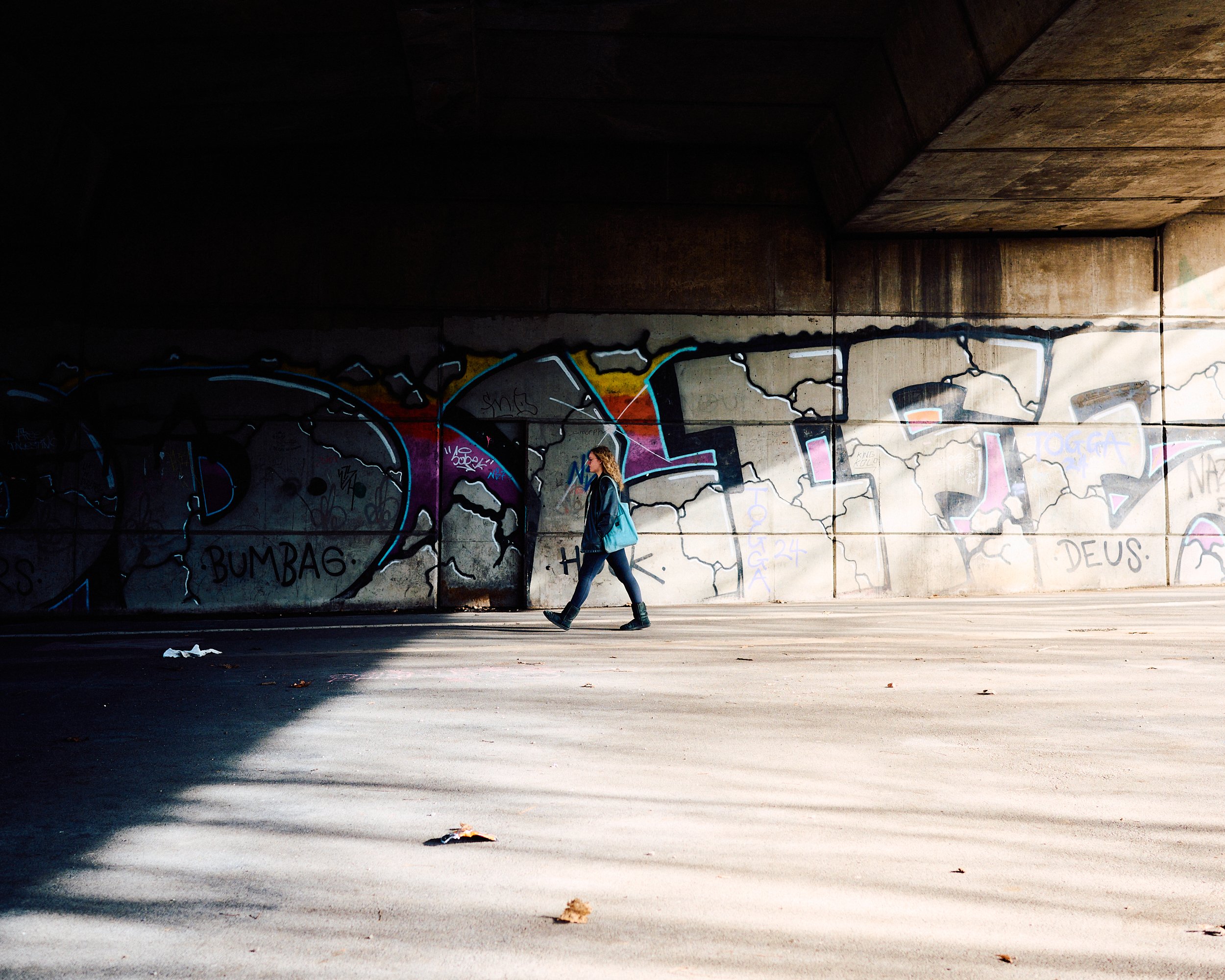 Woman walking in bridge covered with graffiti