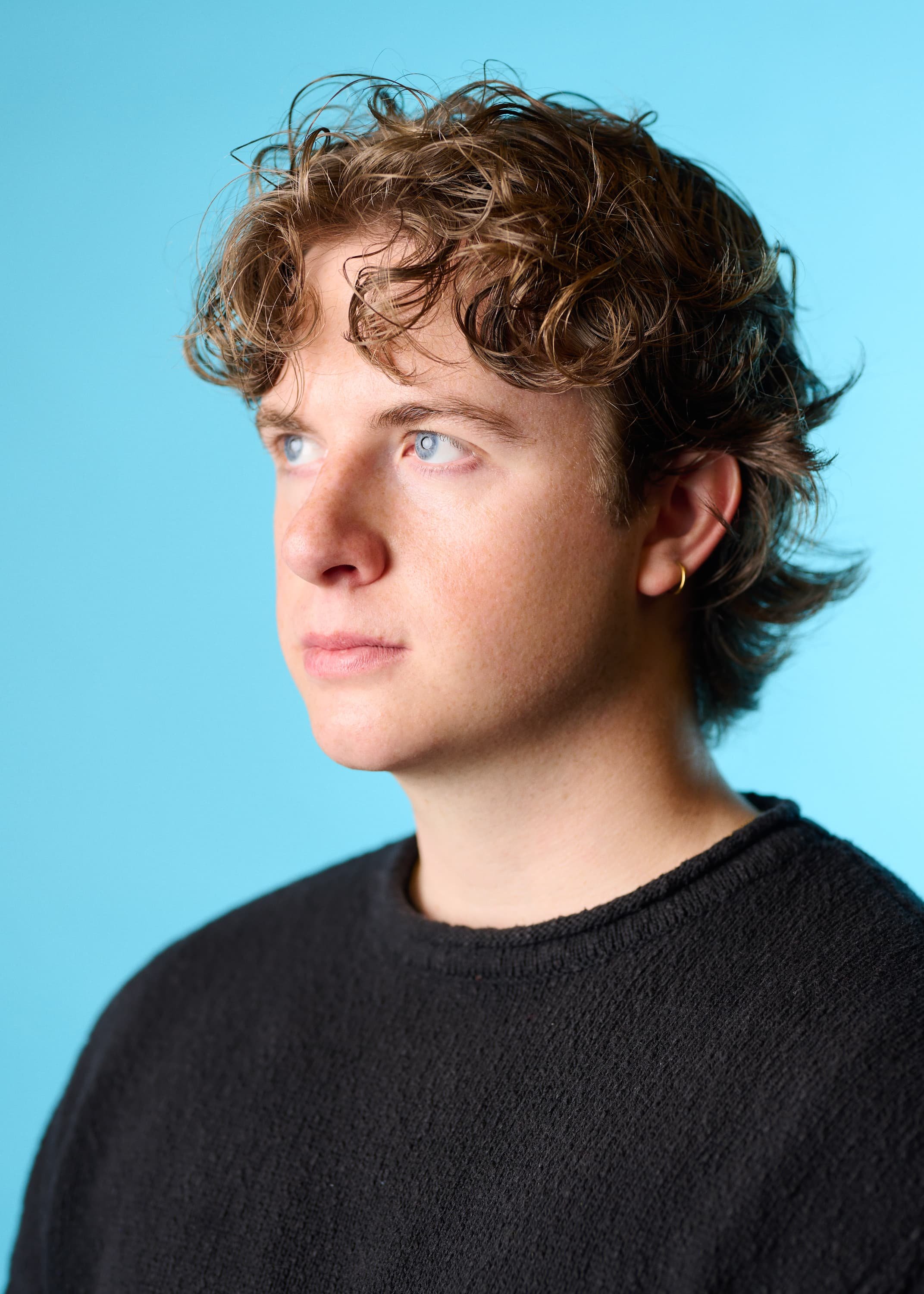 Colour portrait of a man sitting 3/4 quarter angle and looking away from the camera