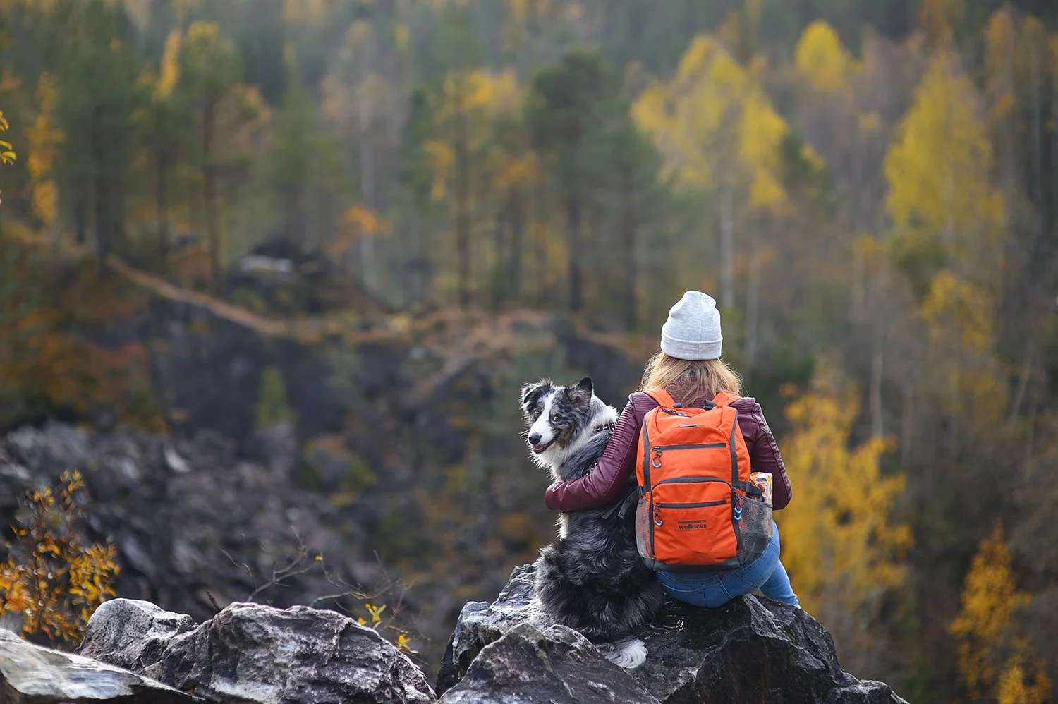   A woman holds onto her dog while resting on a fall hike. Looking for the best dog-friendly hikes in Boulder? Check out our Ultimate Guide on Boulder Hikes and discover your next best hike with your dog.  