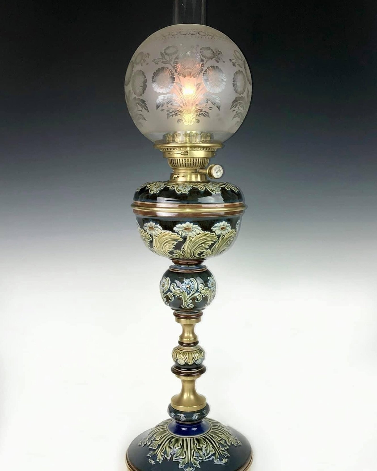 Banquet &ldquo;daisies&rdquo; oil lamp by Doulton &amp; Co. Each glazed ceramic section was hand-sculpted by artist Joan Honey.  33 inches tall. Lambeth, England circa 1890.

The Drake Hall Collection