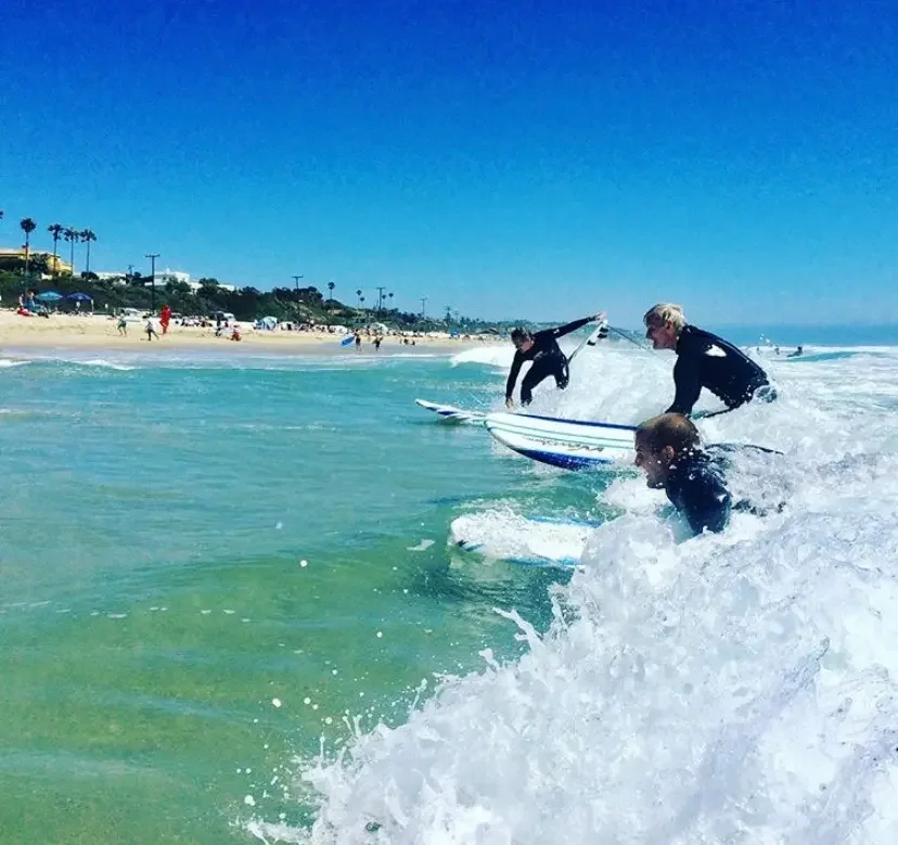 Adult beginner standing up on a surfboard during a Santa Monica surf lesson