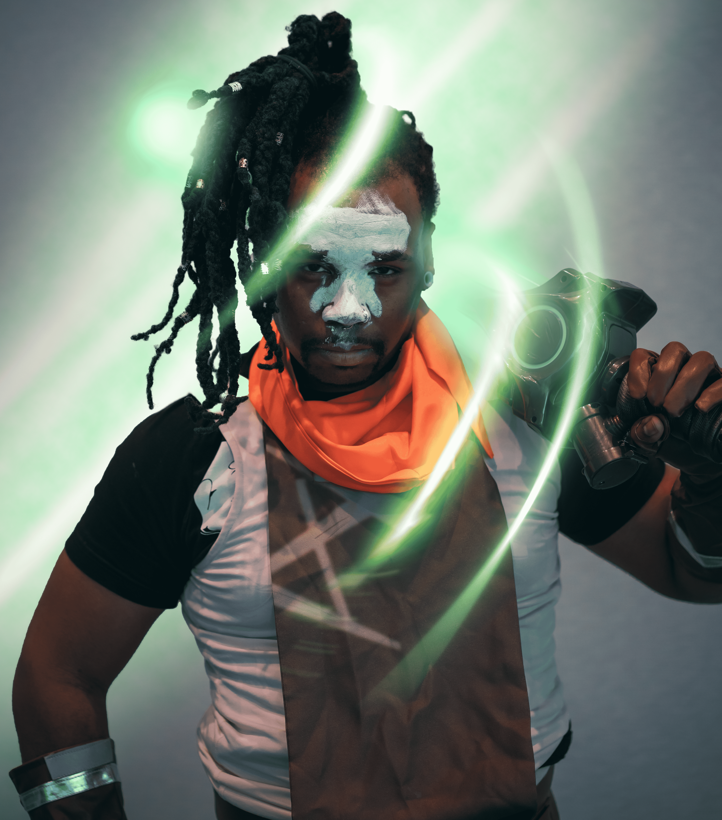 A person with dark skin and white face paint looks directly at the camera, holding a gun with glowing green laser beams and light effects surrounding him, wearing a sports jersey and gloves.