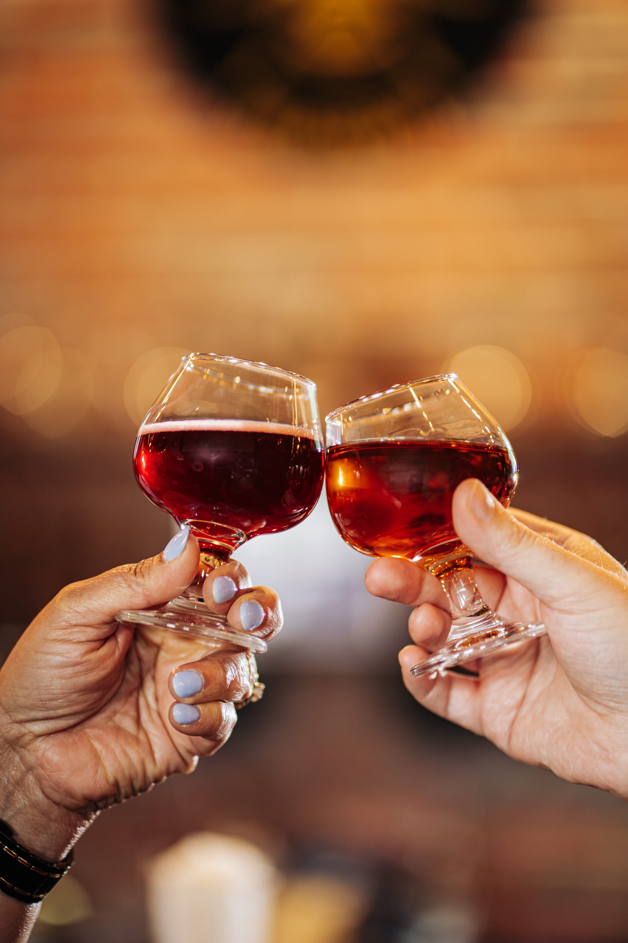 Two people holding wine glasses filled with red wine in a toast.