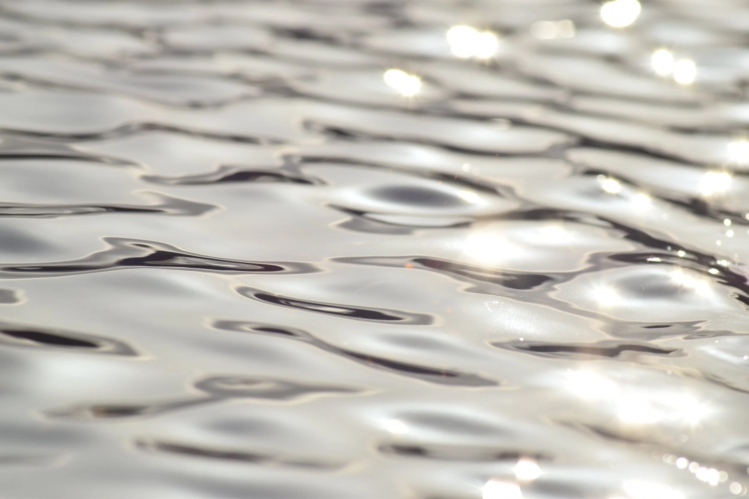 Close-up photograph of shimmering water with gentle ripples and highlights taken by Megan Hall.