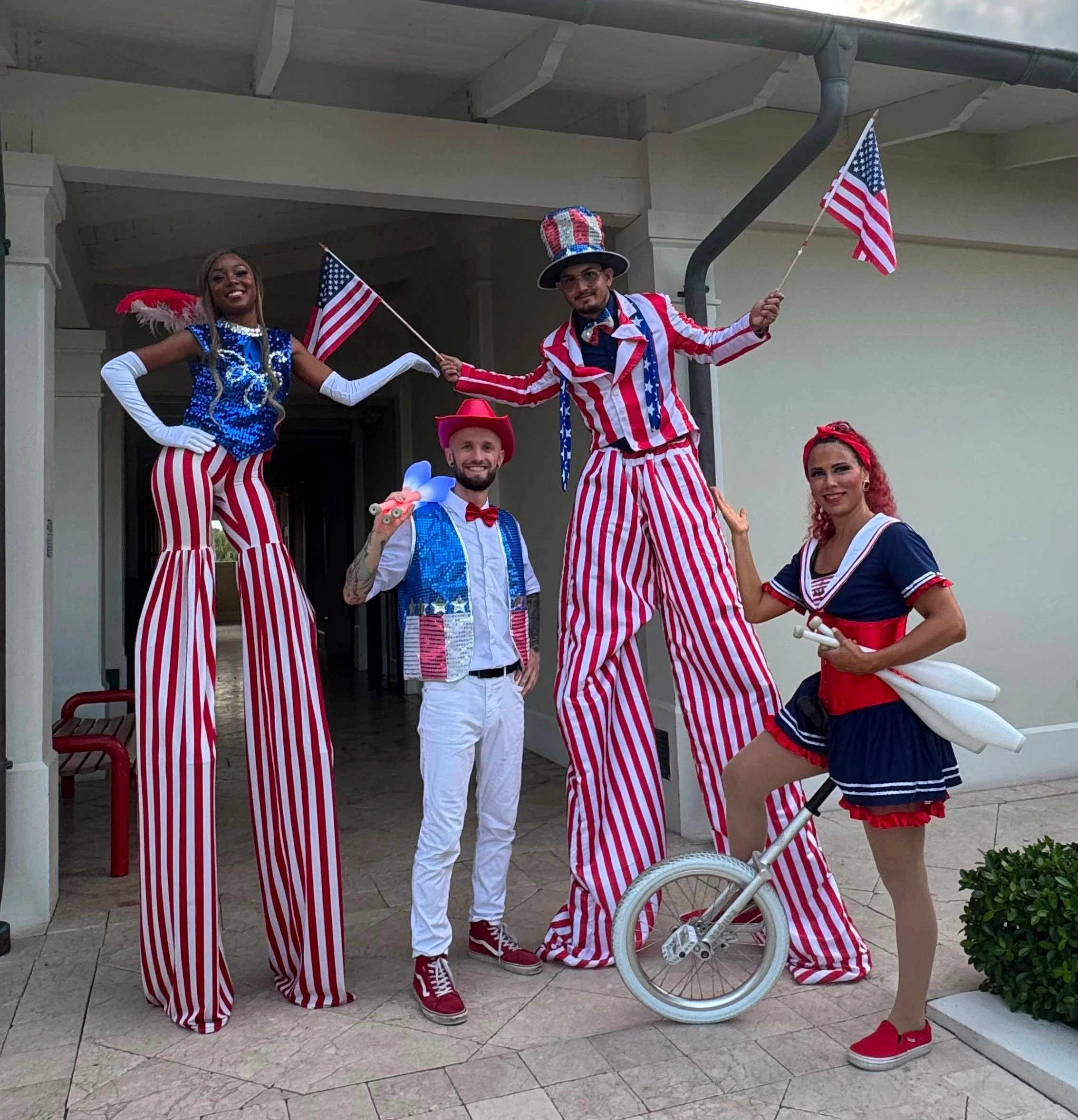Unlicler and Juggler Female Performer in 4th of July Sailor Costume next to two Stilt Walkers and a Juggler