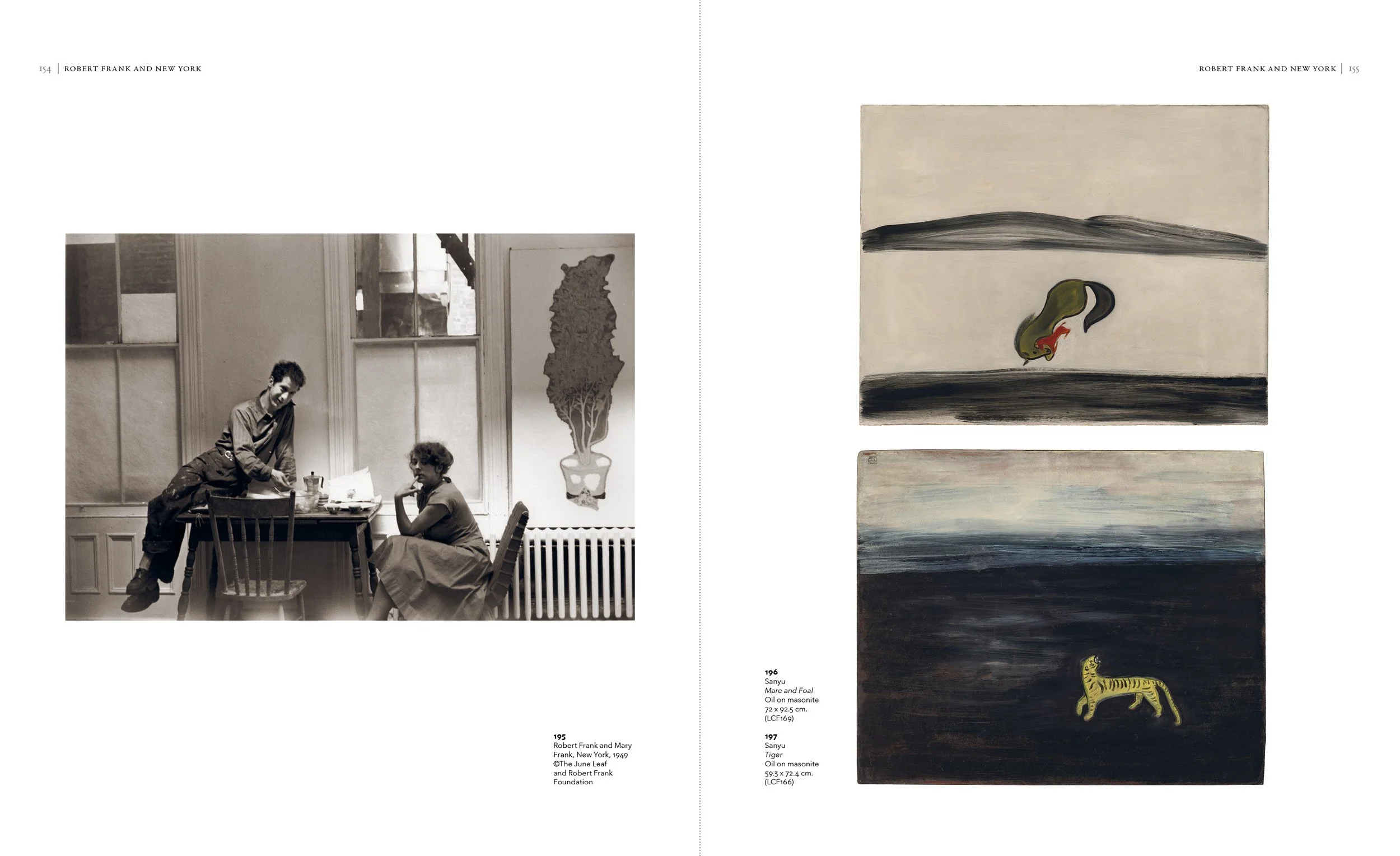 A black and white photograph of Robert Frank and Mary Frank sitting at a table in a room with windows and a potted plant wall hanging. Two paintings are displayed on the right side: the top painting depicts an abstract landscape with a swan, and the 