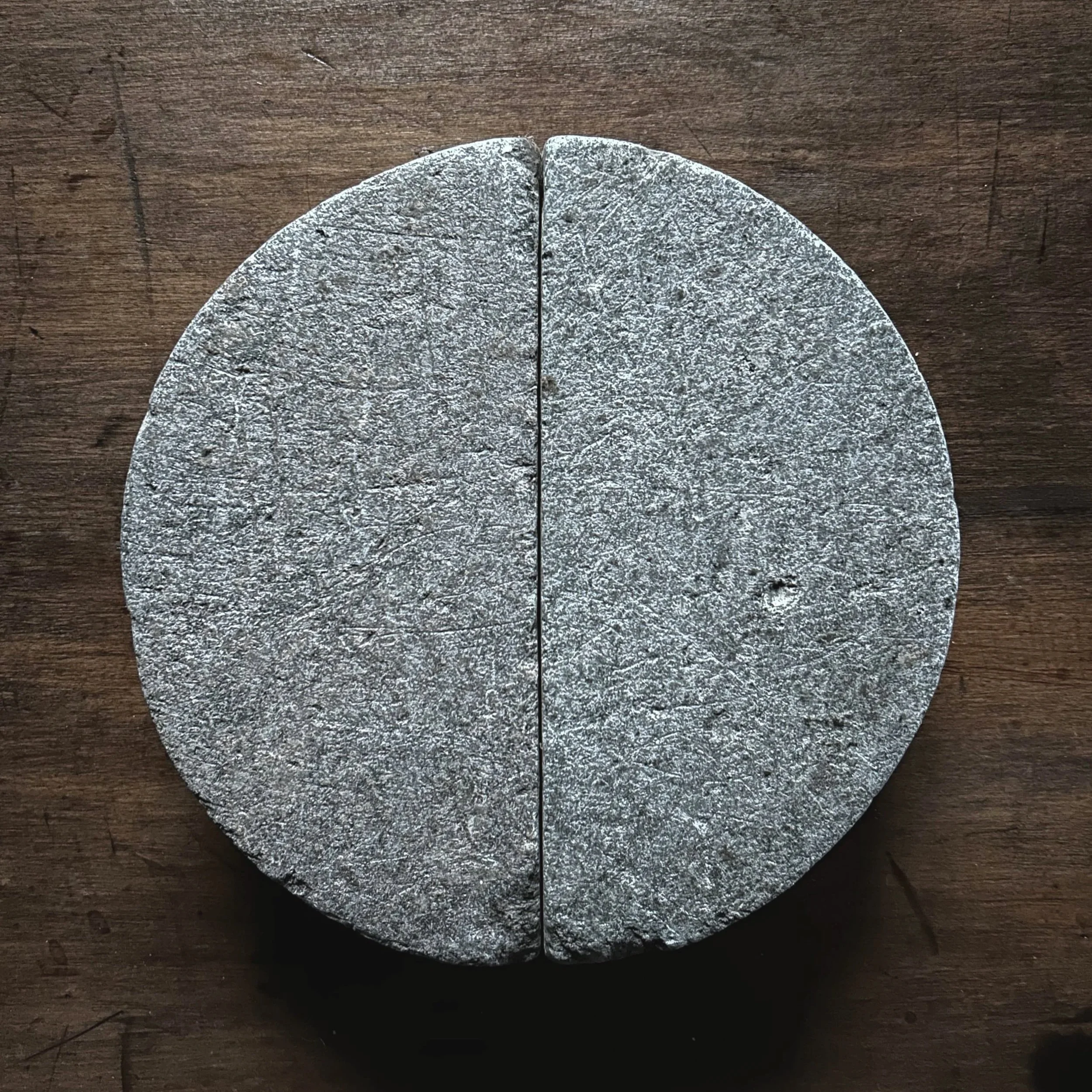 A round, stone or concrete disc on a wooden surface.