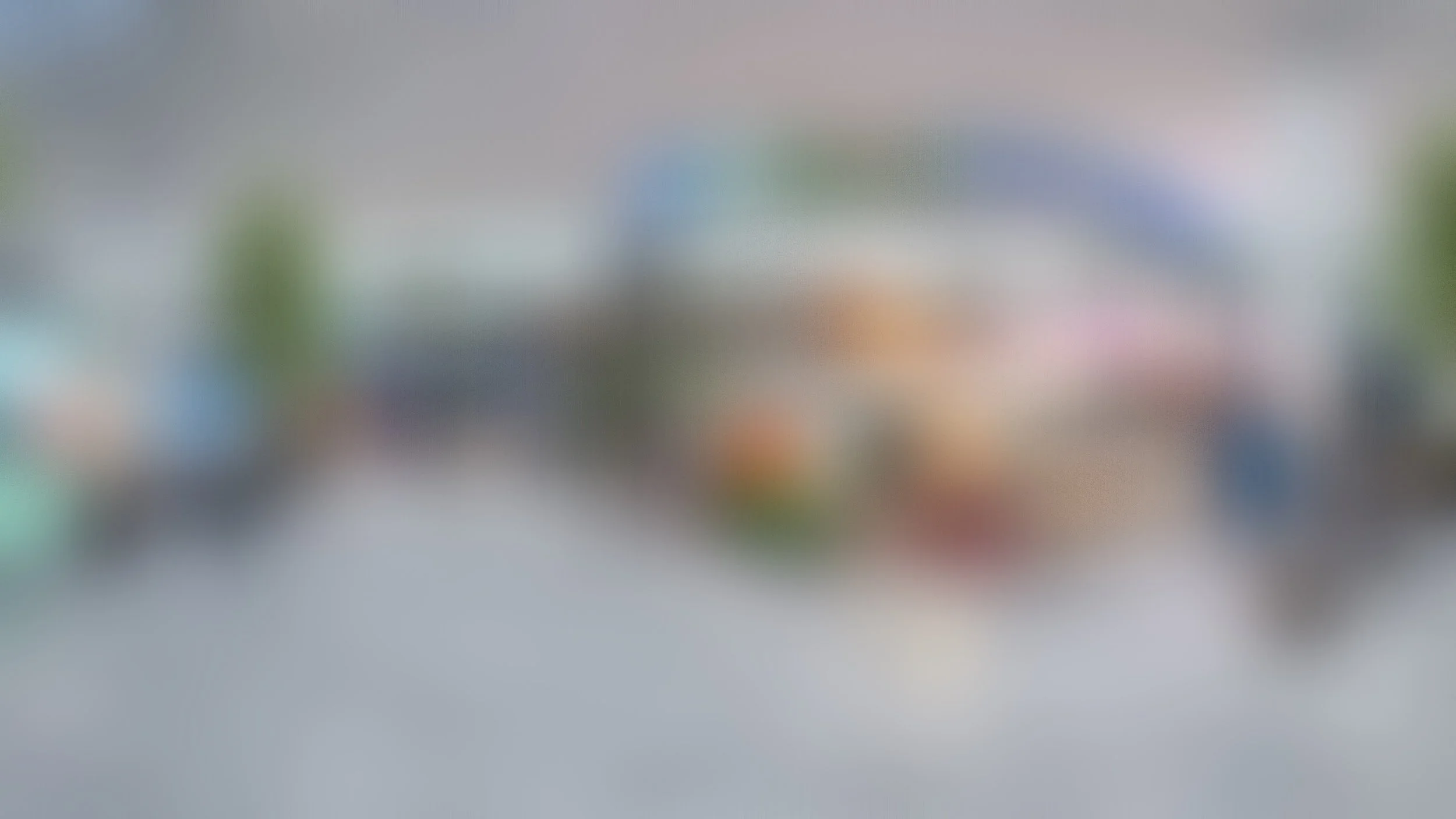 Image of a blurred outdoor event or fair with booths and tents, and people walking around.