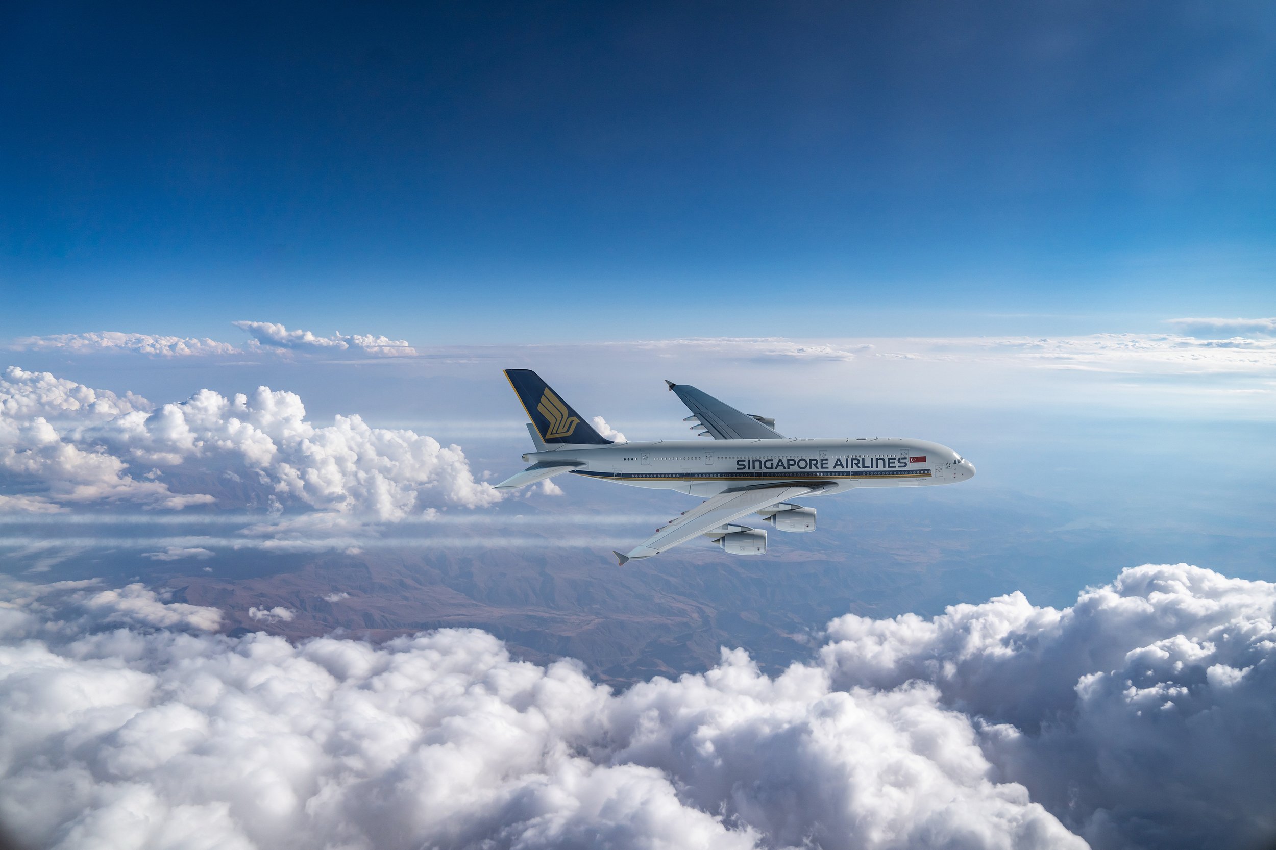 Singapore Airlines airplane flying above clouds in a clear blue sky