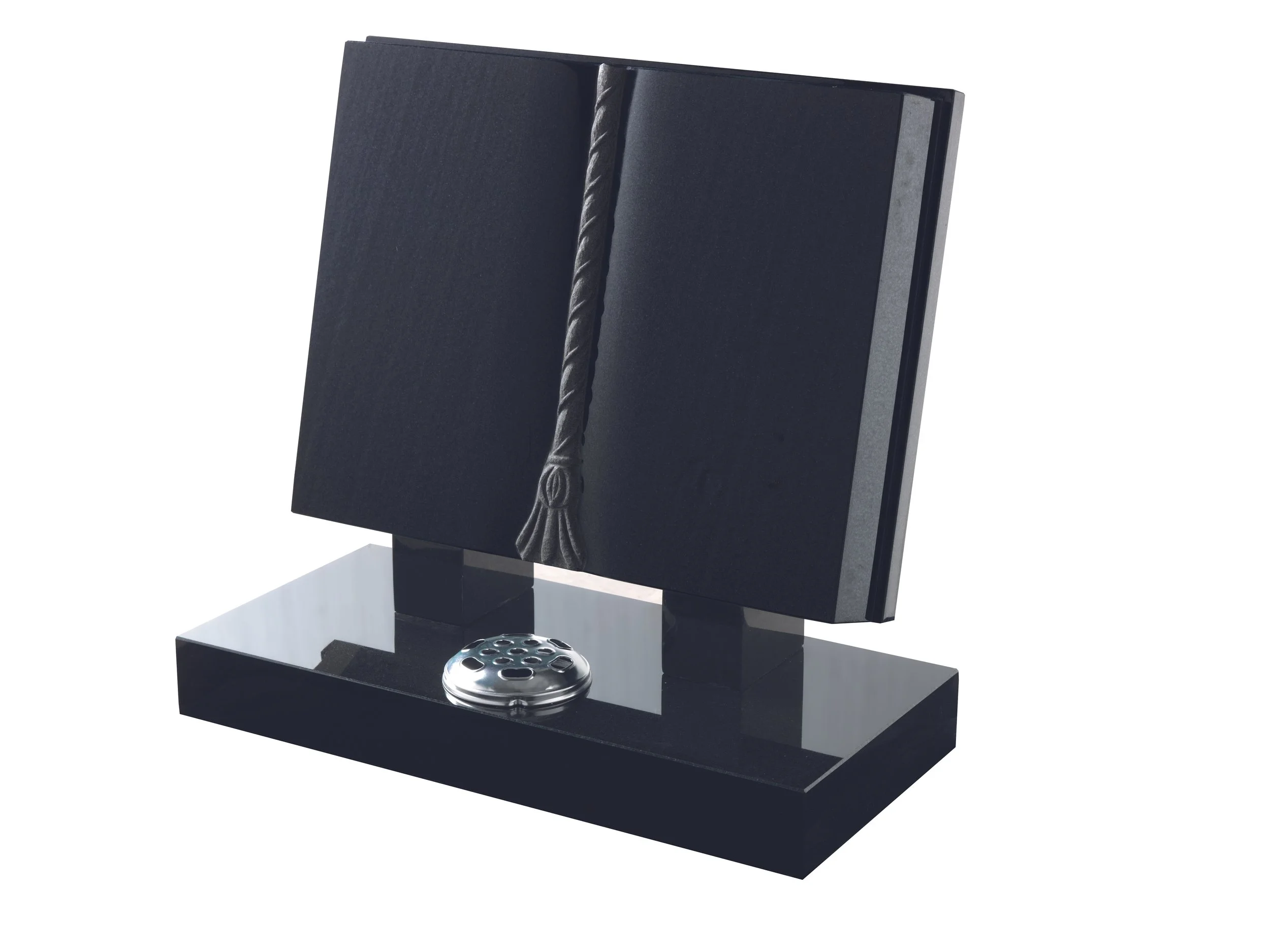 Black desk set featuring a book holder resembling an open book with a tassel hanging on the side, mounted on a black base with a metallic disc in front.