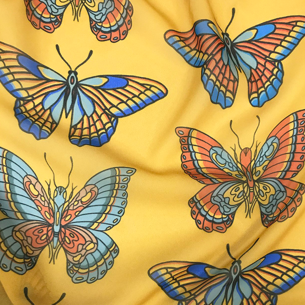 Blue and orange butterfly fabric design on a mustard-colored background by Laurie Shipley Design.