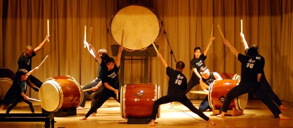 A group of performers playing traditional Japanese drums on stage.