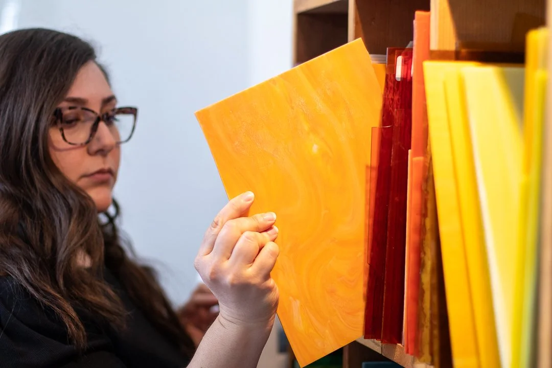 Photo of Instructor, Jordan Taub, pulling a sheet of glass for a project.