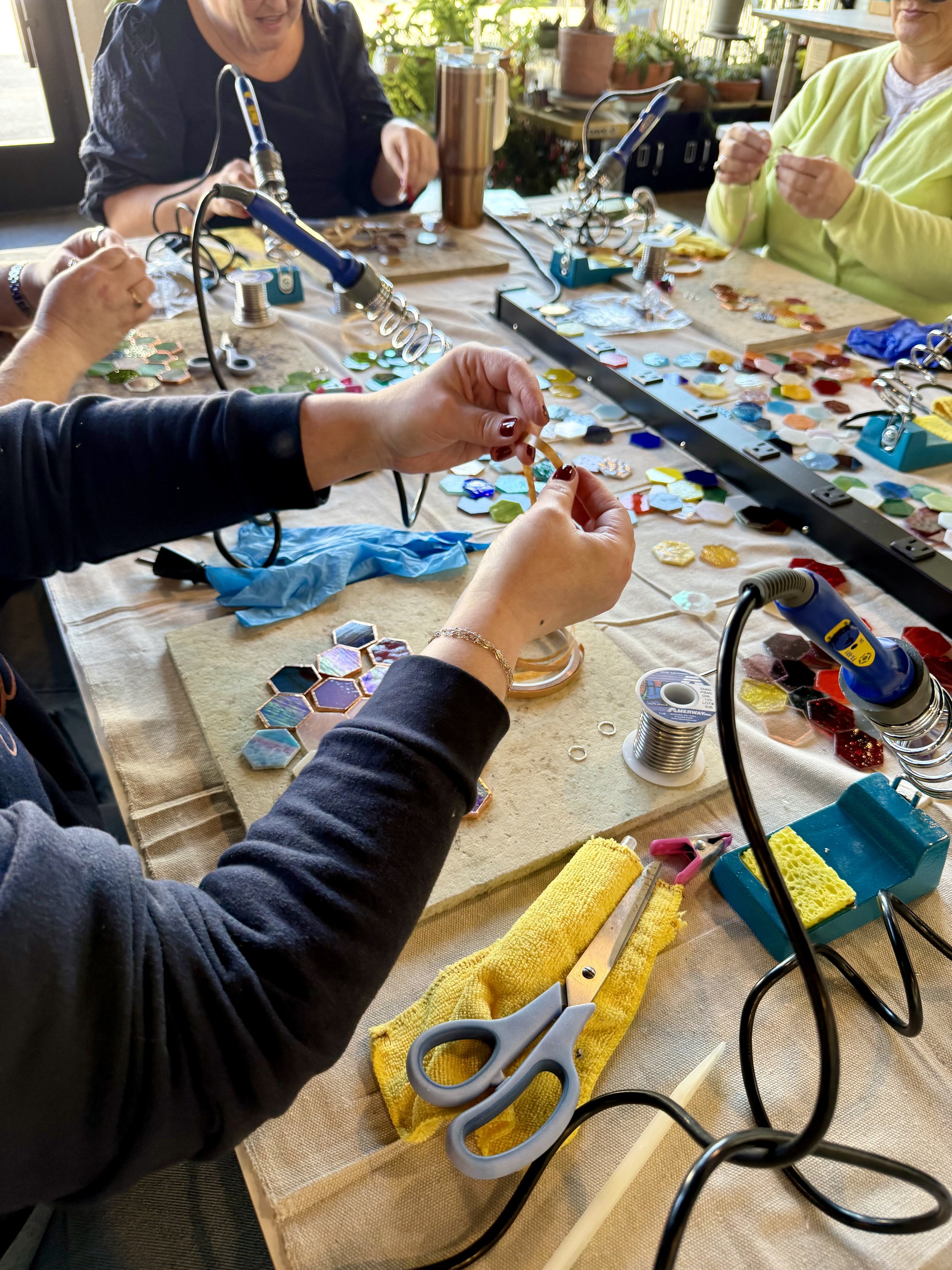Image of students at a stained glass class in the middle of copper wrapping glass pieces.