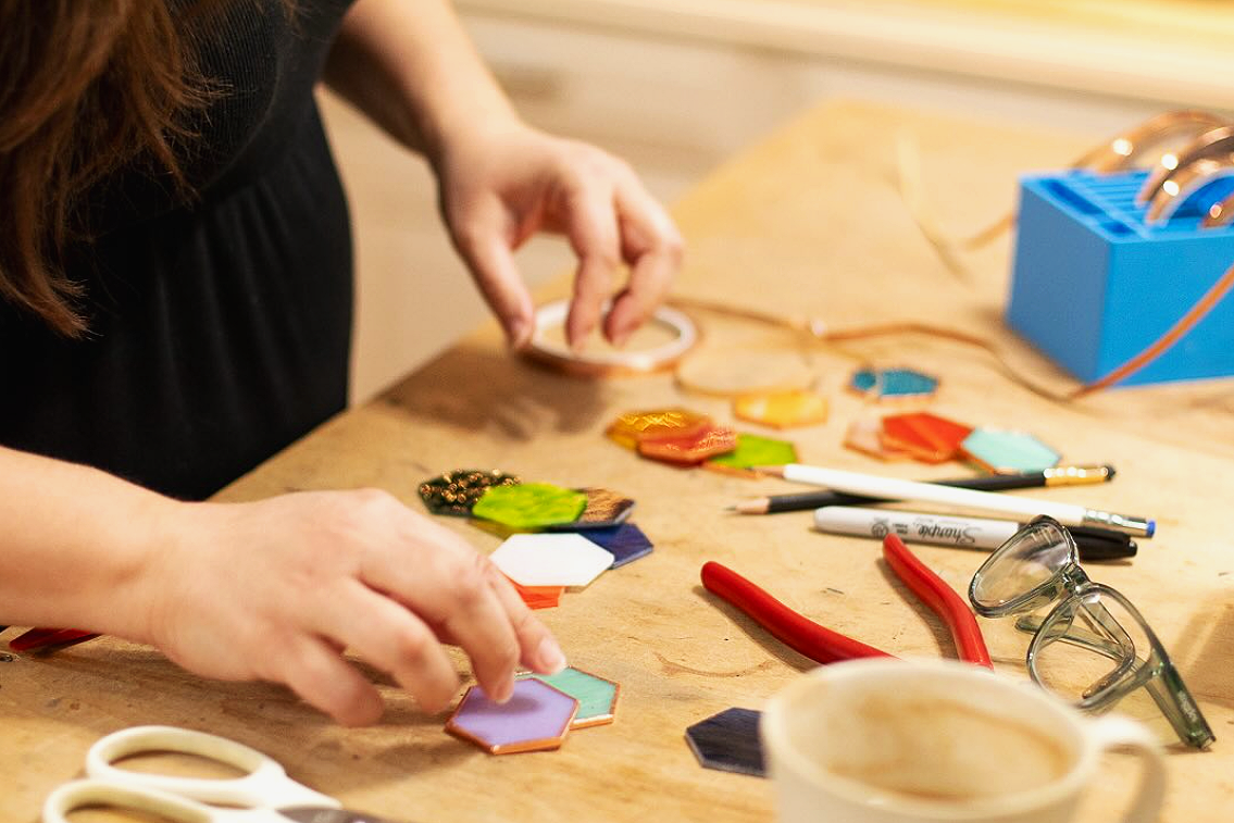 An artist arranging pieces of cut stained glass into a finished work