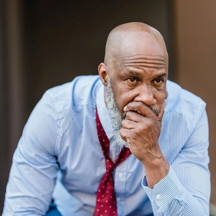 Man sitting with his hand over his mouth appearing overwhelmed by intrusive thoughts.