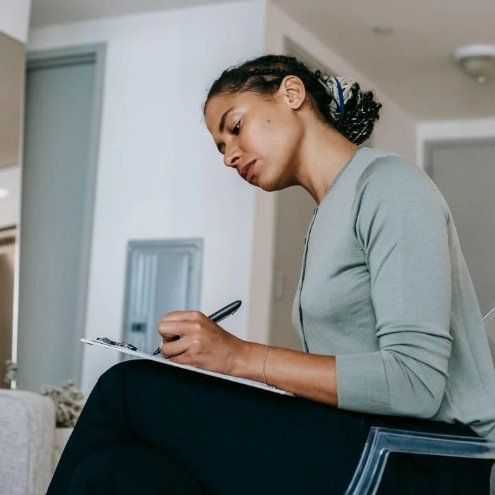 Therapist attentively writing on clipboard during a therapy session