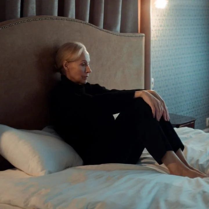 Person sitting quietly on a bed while recalling a traumatic memory.
