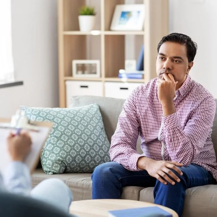 Man reflecting deeply during EMDR therapy with counselor at office