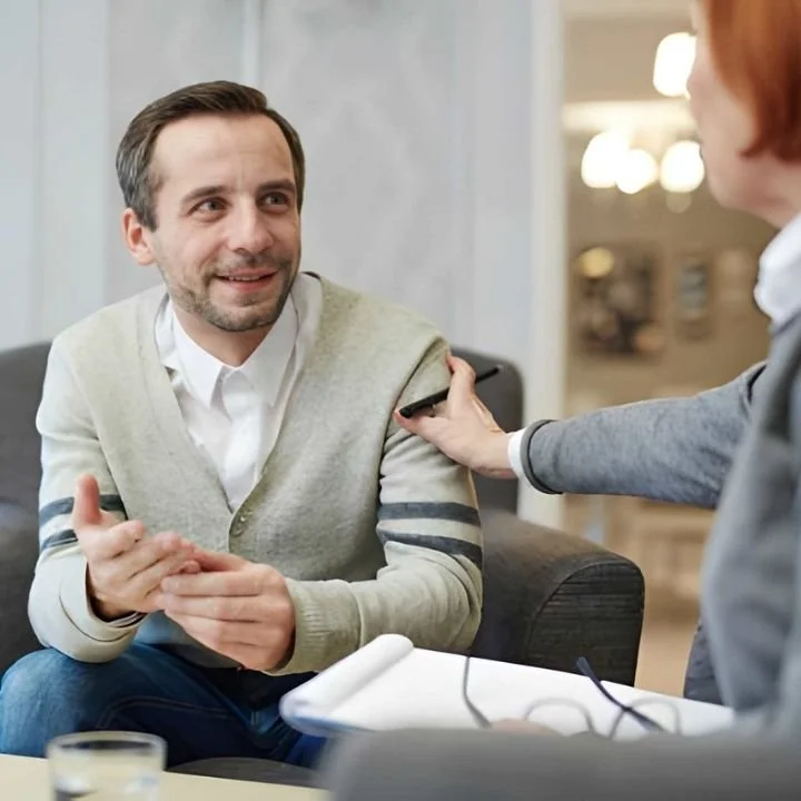 Man smiling while talking with a therapist after EMDR therapy progress.
