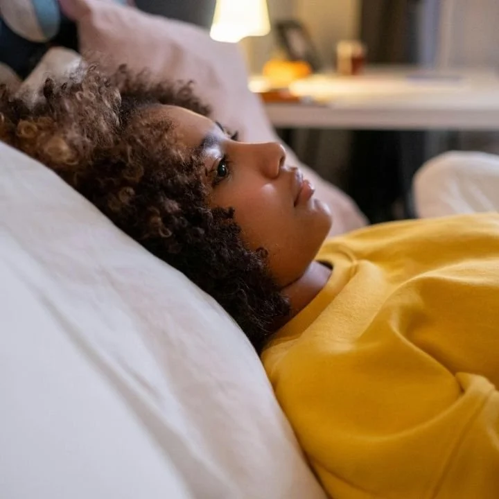 Woman lying awake in bed, looking distressed and unable to sleep.
