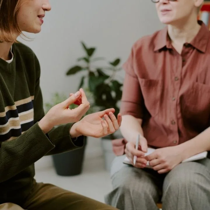 Close-up of hands gesturing while discussing OCD intrusive thoughts in cognitive behavioral therapy session.
