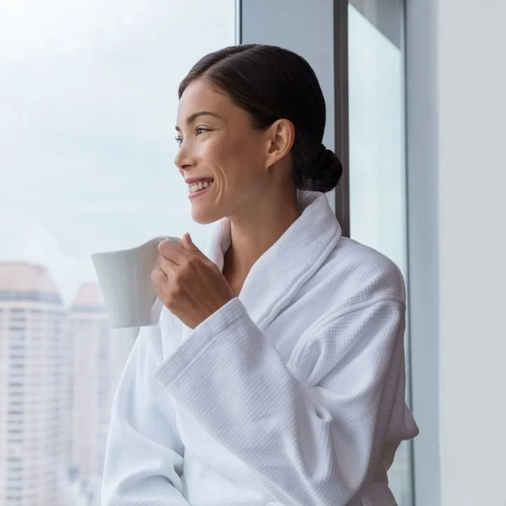 Woman smiling peacefully by window holding cup