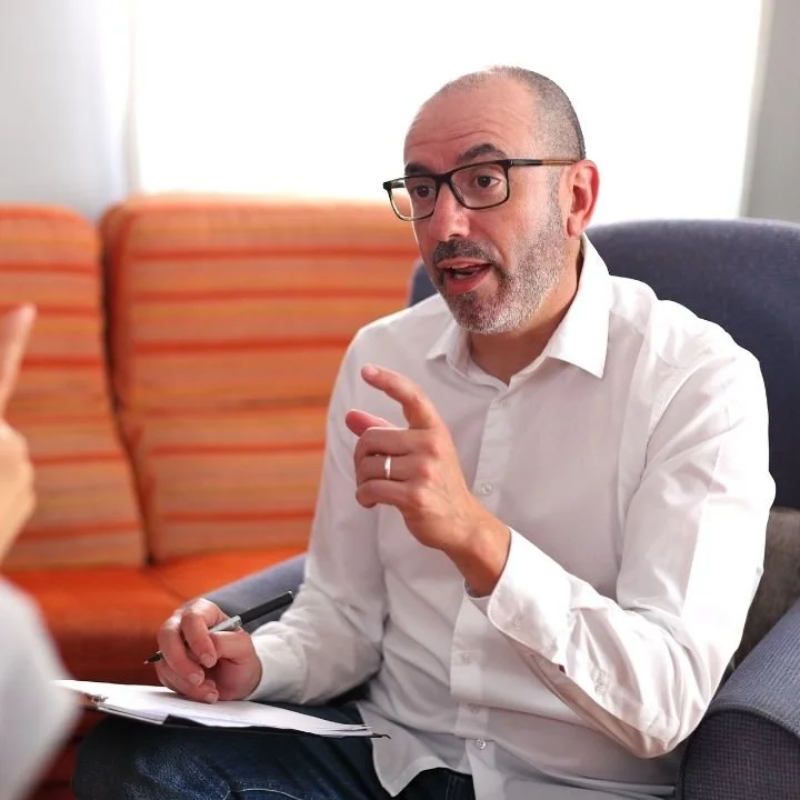 Male therapist explaining during session while holding clipboard