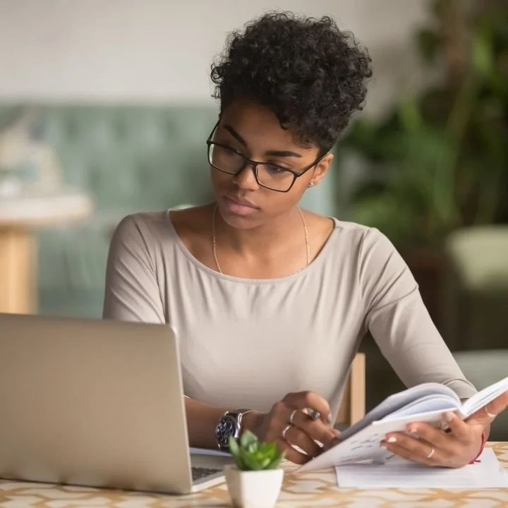 Focused woman reviewing notes on laptop in calm workspace